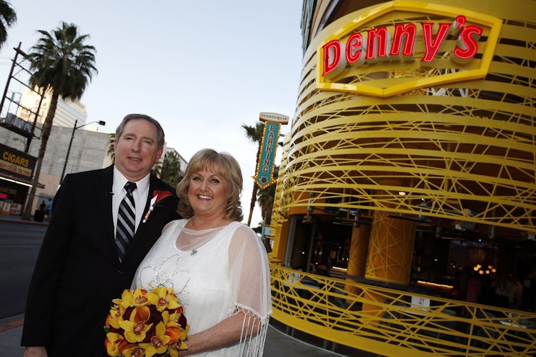A bride and groom standing and smiling outside of the Denny's Chapel in Las Vegas, NV.