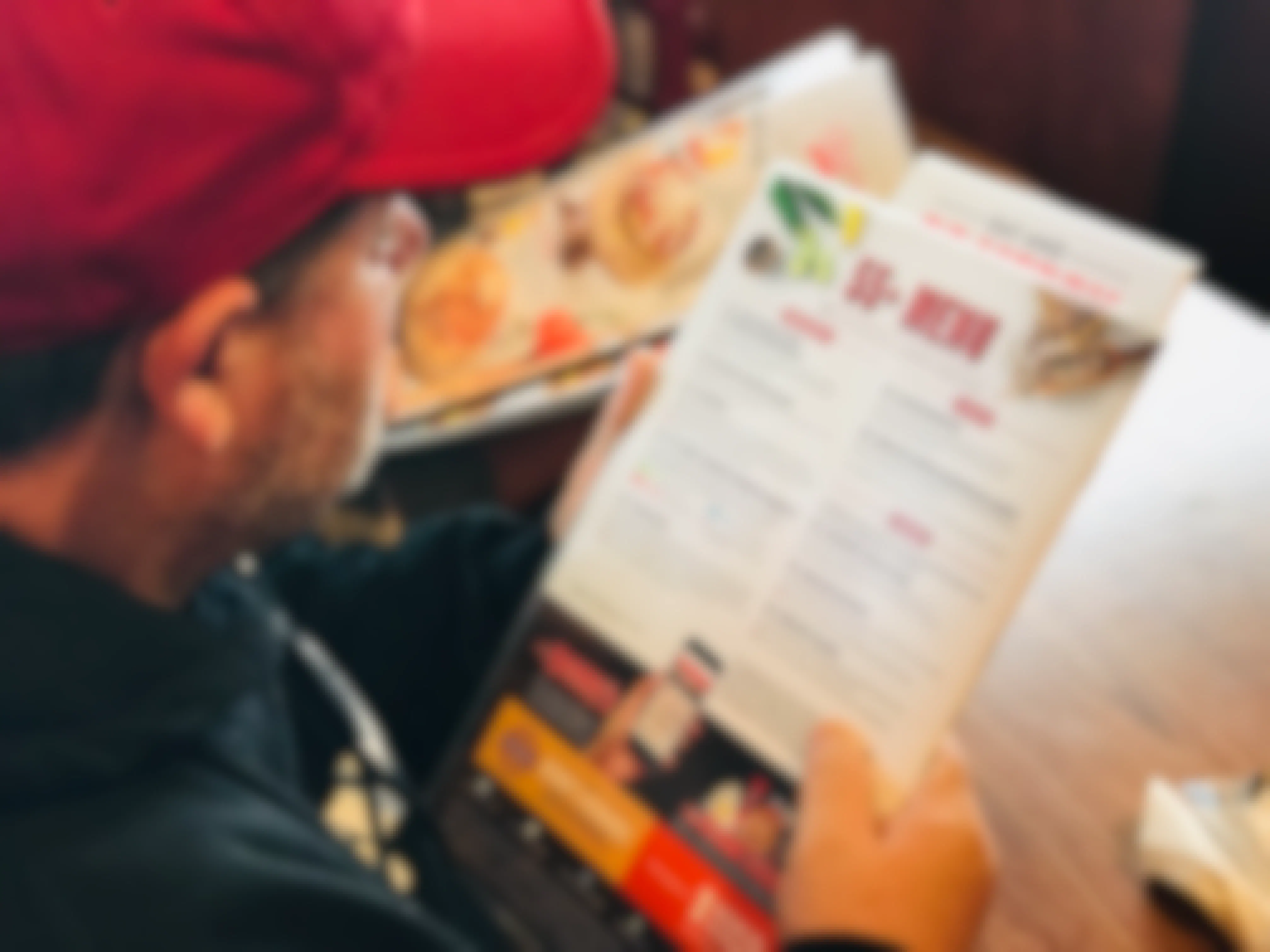 A man reading from the 55+ menu page while sitting in a booth at Denny's.