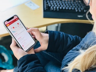 A person looking down at their phone which is displaying the Denny's mobile app's page for store locations.