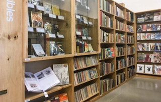 A view down a large bookshelf filled with books in an aisle in a bookstore.