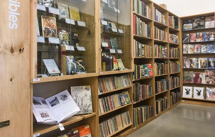 A view down a large bookshelf filled with books in an aisle in a bookstore.