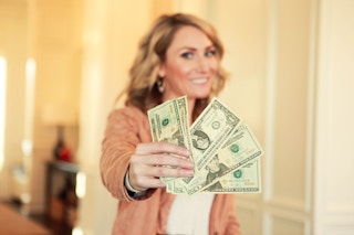Woman holds fanned out money in the foreground