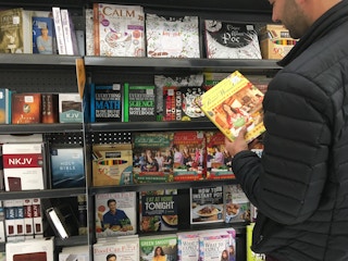 someone looking at pioneer woman book next to book shelf