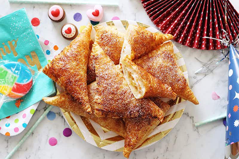 turnovers dusted with sugar on a paper plate