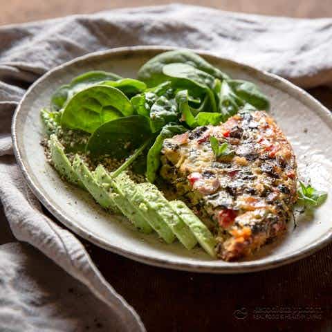 avocado and spinach on a plate next to a frittata