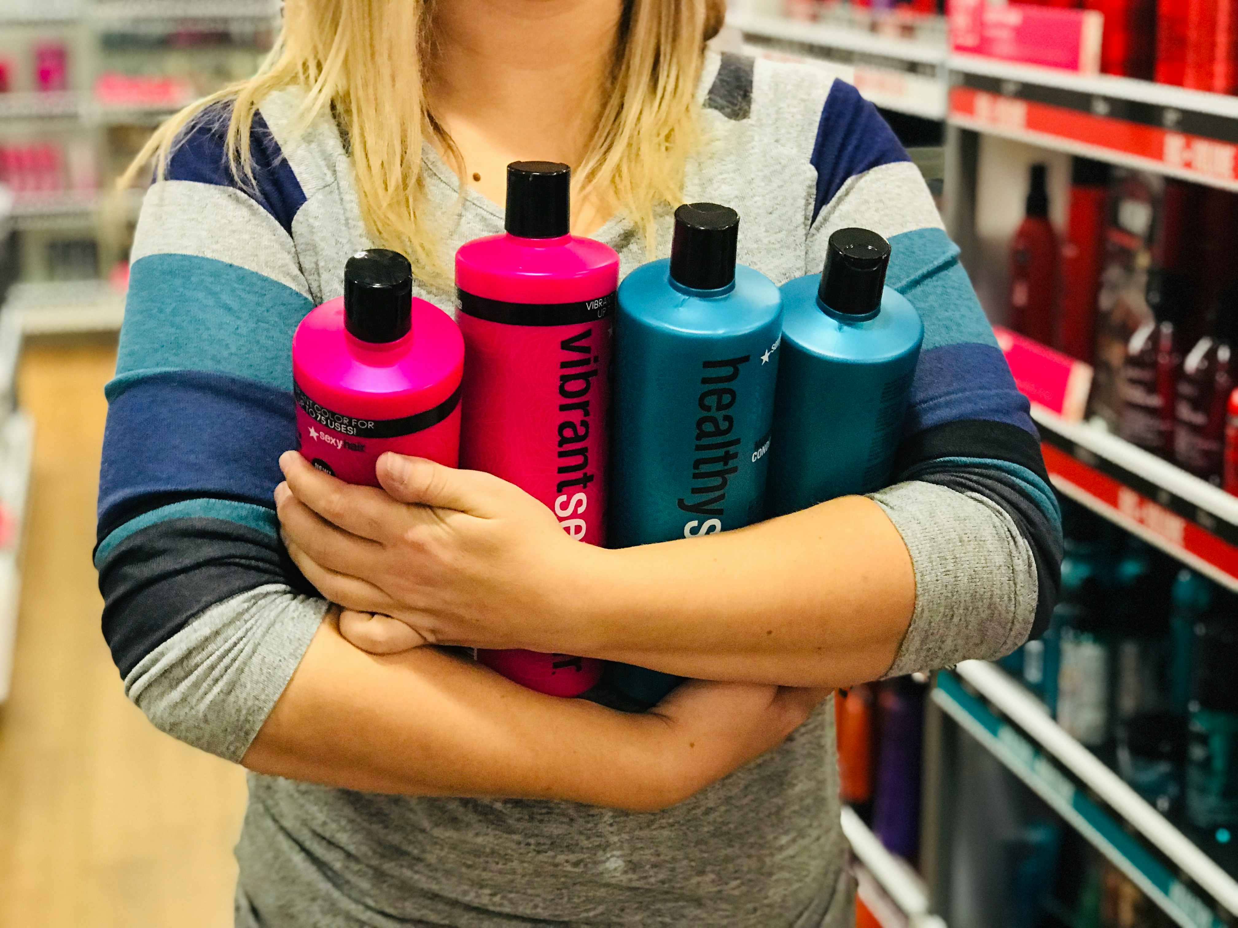 Woman holding four one-liter bottles of shampoo inside Ulta.