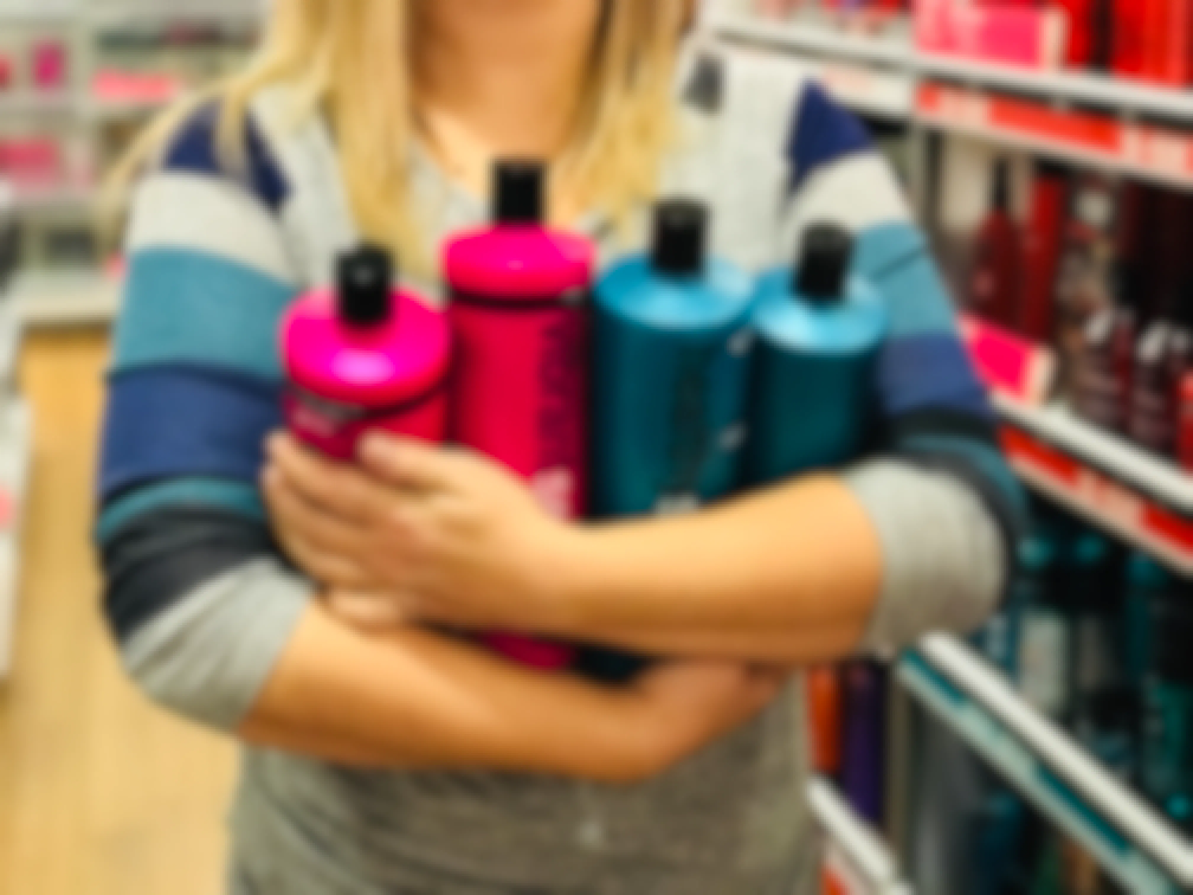 Woman holding four one-liter bottles of shampoo inside Ulta.