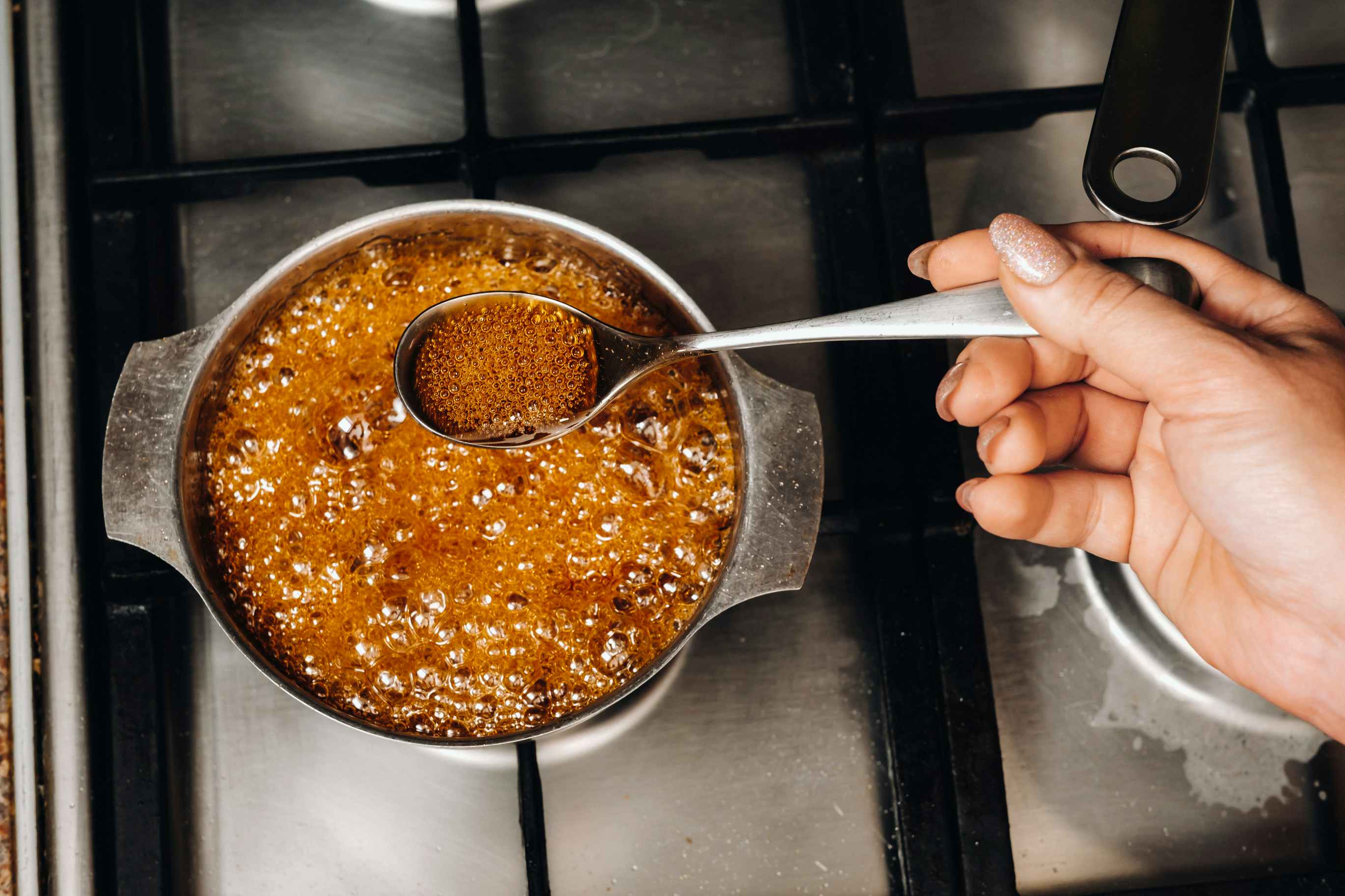 Someone melting sugar in a pan to make homemade candy