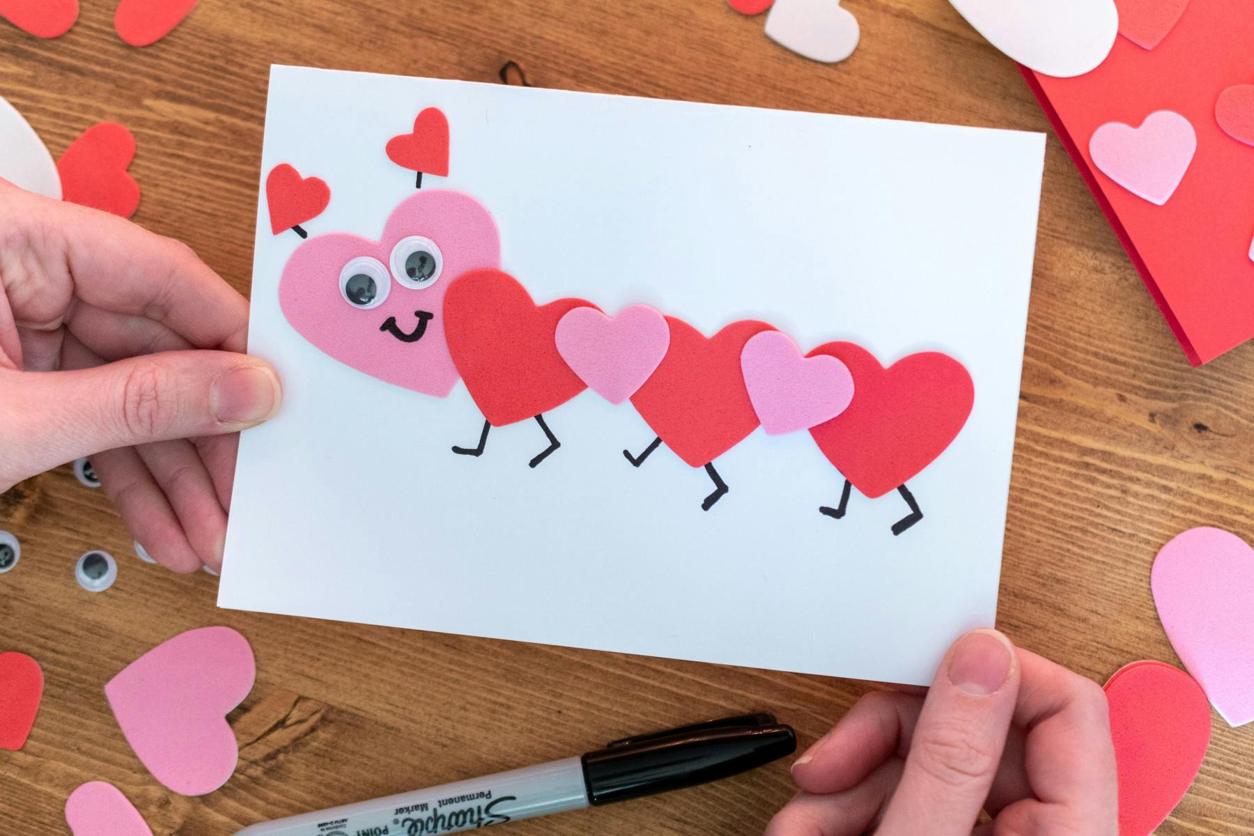 someone holding card with heart caterpillar