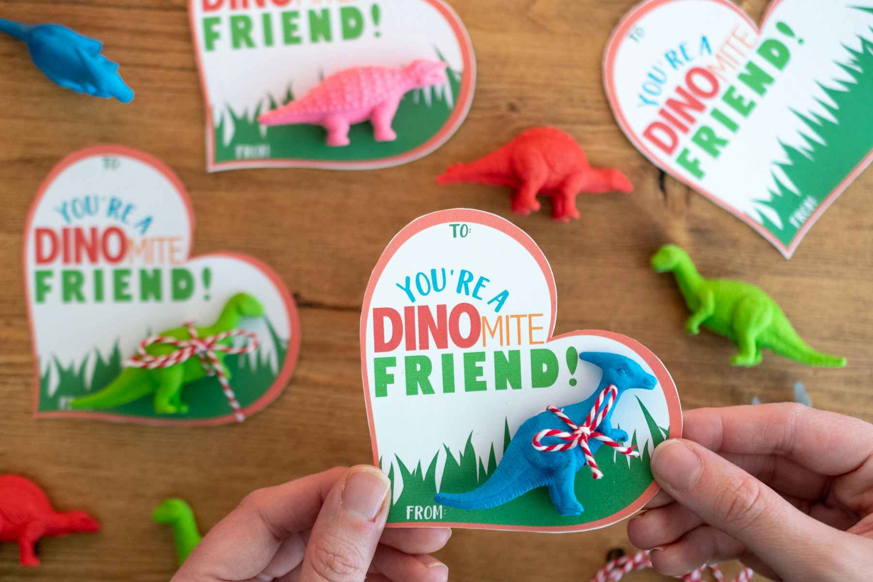 someone holding a you're a dinomite friend card with toy dinosaur