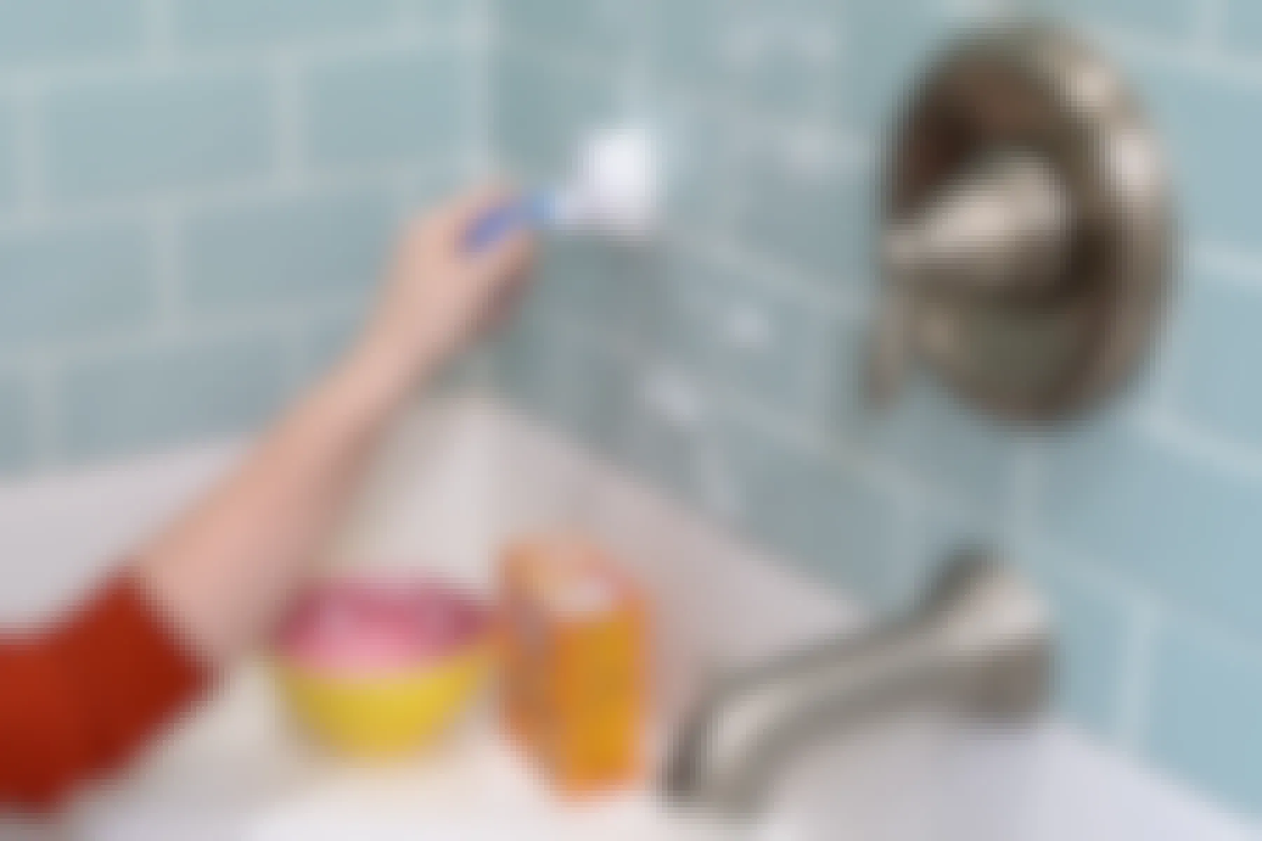 A person scrubbing bathtub tile with baking soda.