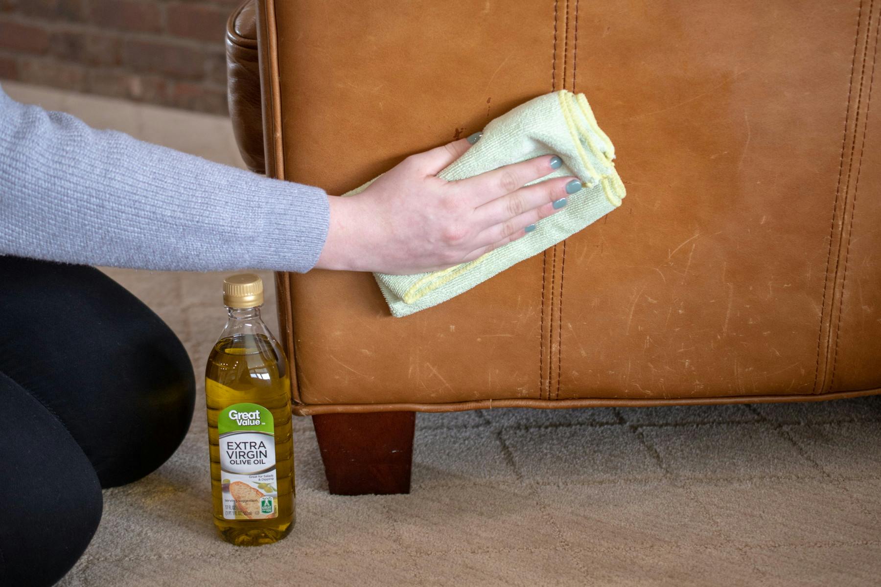 someone wiping couch with rag next to olive oil