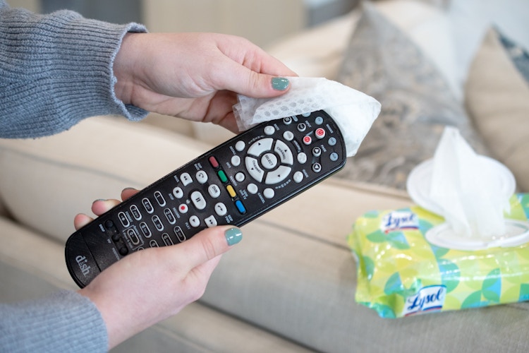someone wiping remote with wipe