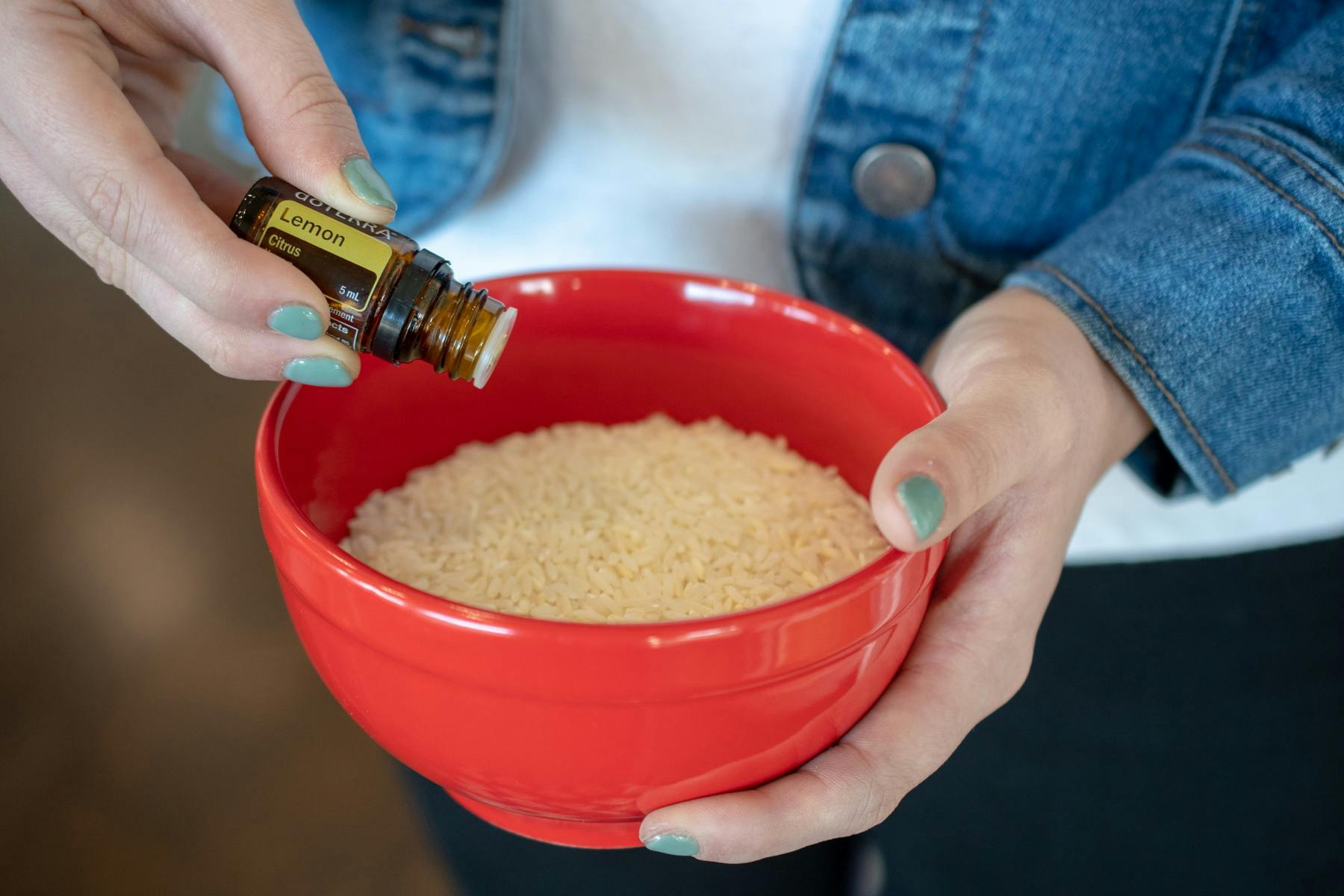 A woman adding a few drops of essential oil to a bowl of rice