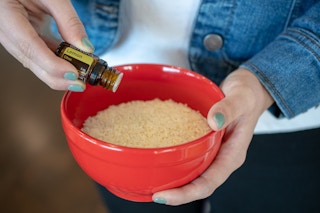 A woman adding a few drops of essential oil to a bowl of rice