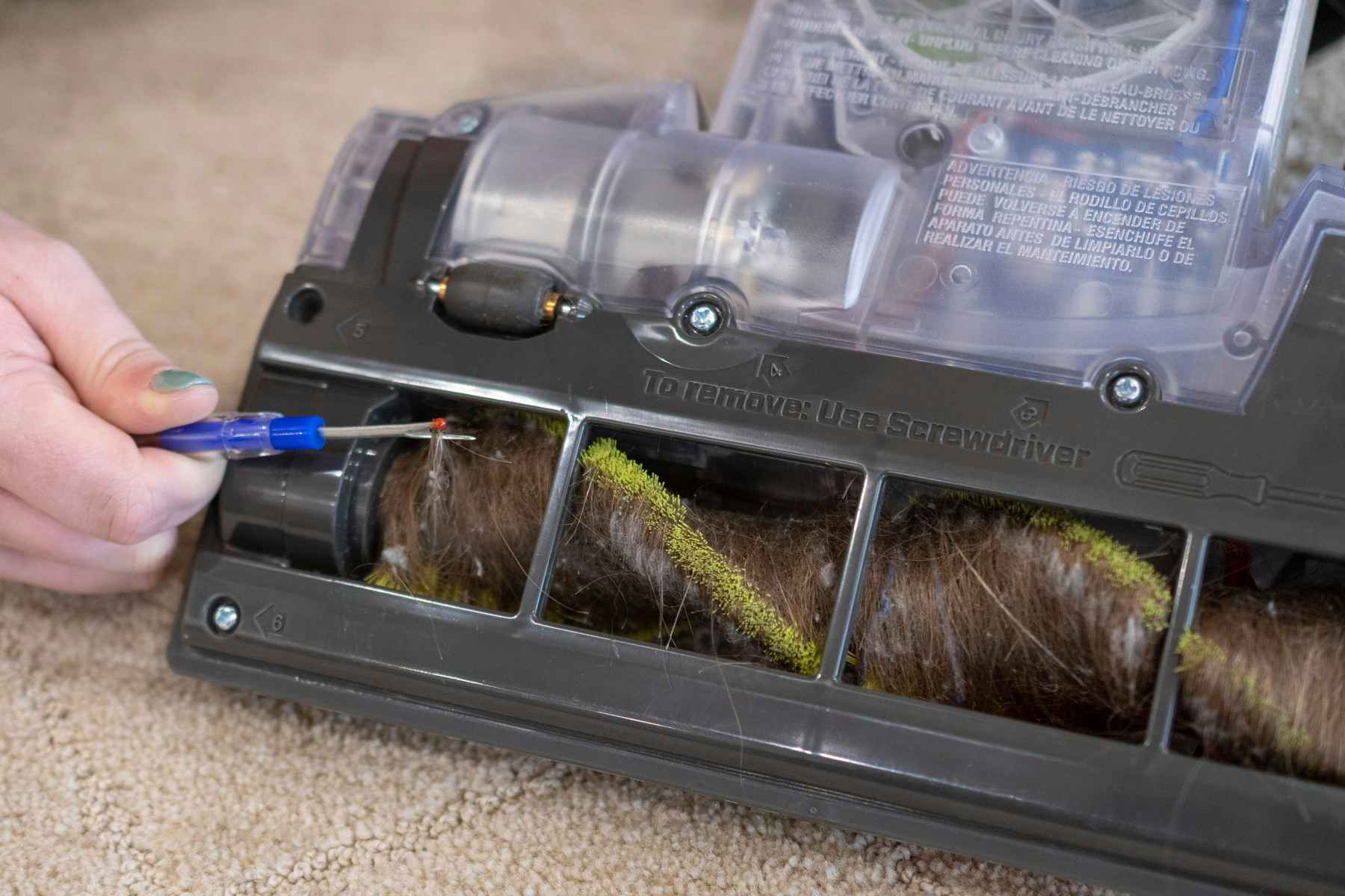 someone using seam ripper to get string out of vacuum