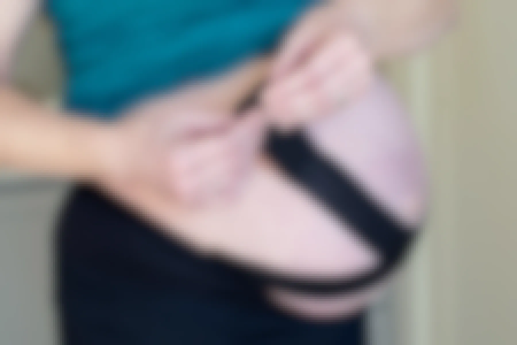 A pregnant woman applying kinesiology tape to her belly.
