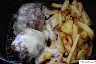 burger patties smothered in cheese with fries in the same air fryer basket