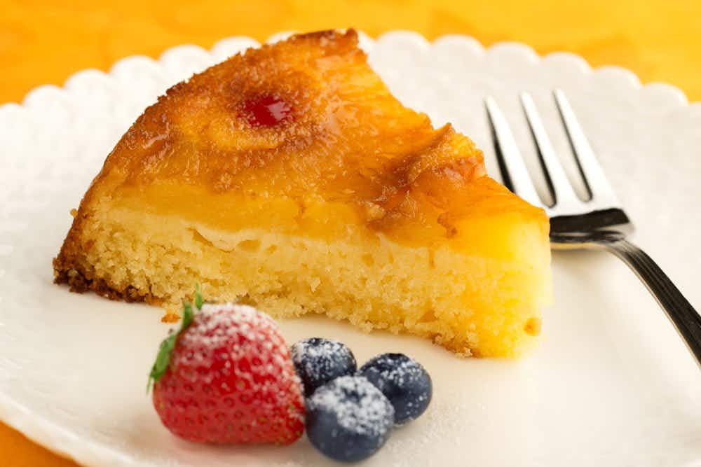 A slice of pineapple cake on a plate with berries