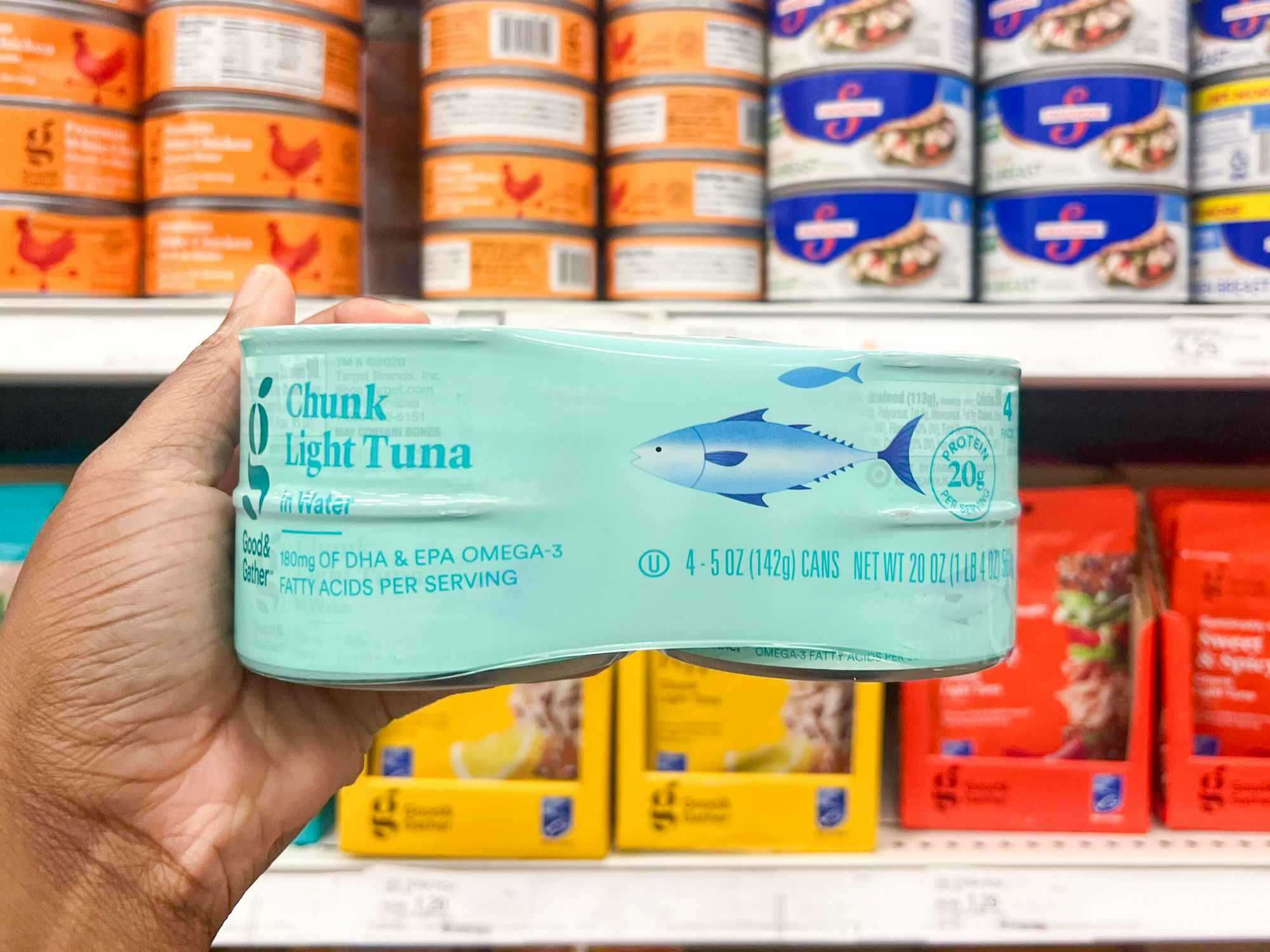 xSomeone holding up a 4-pack of Good & Gather light chunk canned tuna in Target