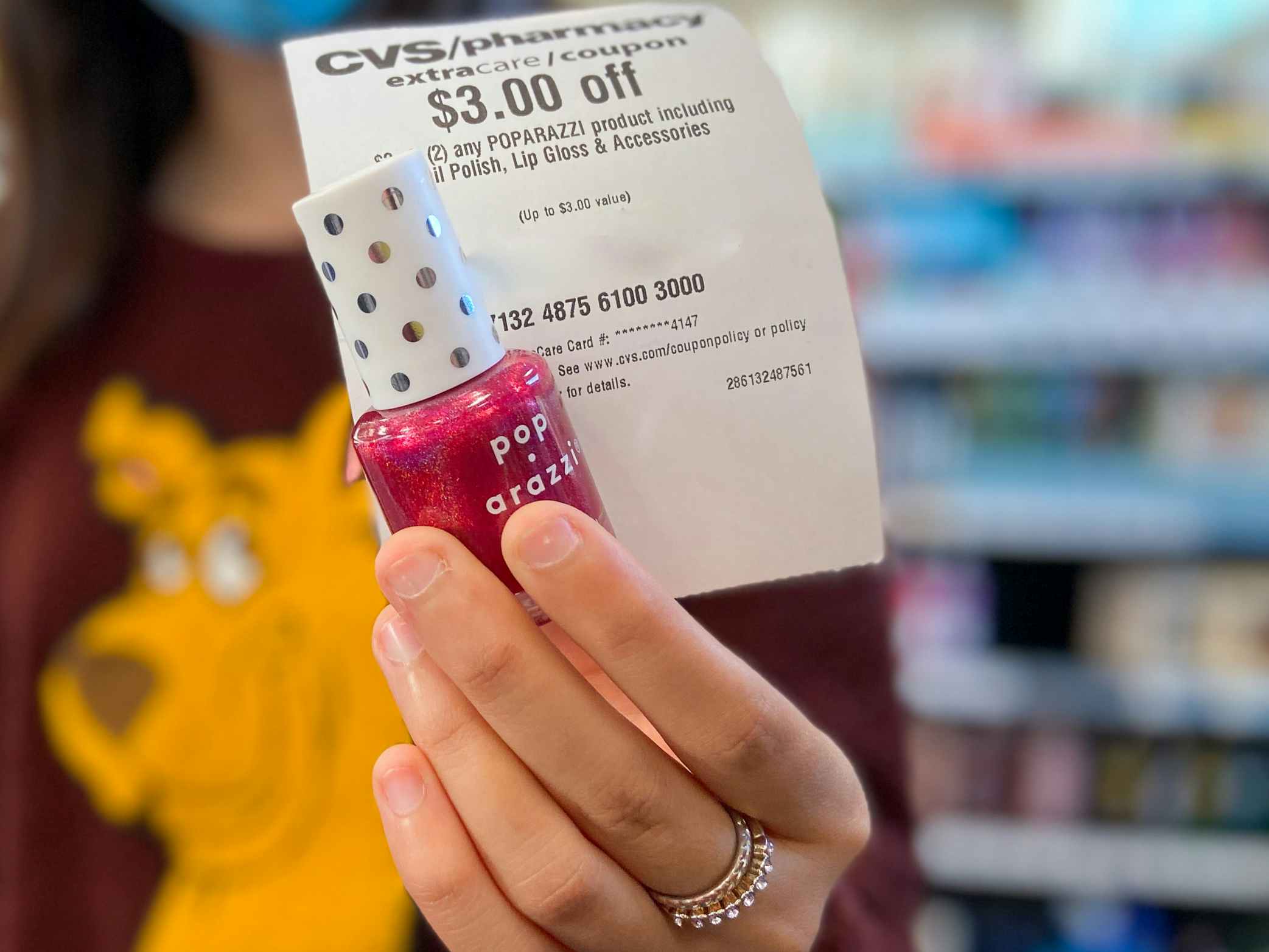 a person holding up nail polish and a coupon from cvs