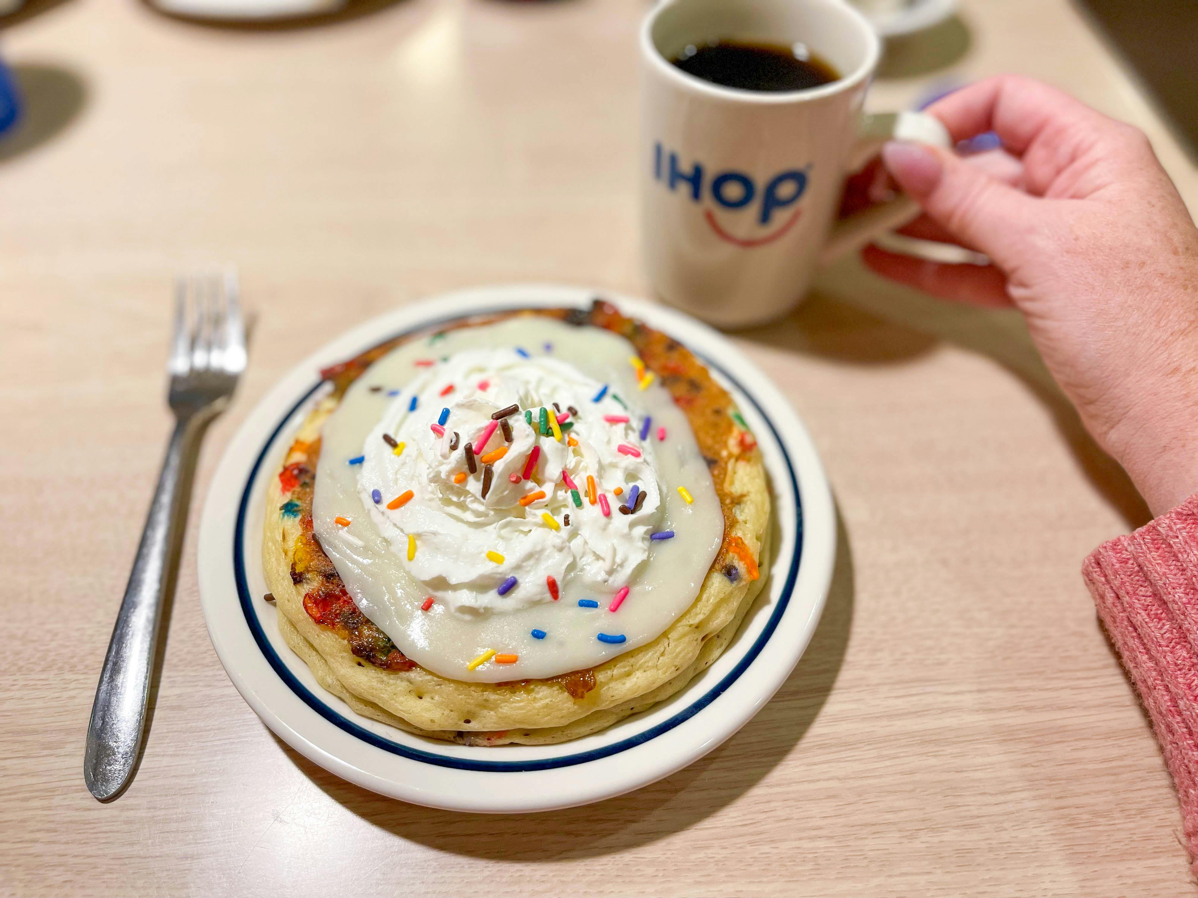 ihop cupcake birthday pancakes on a plate next to a cup of coffee in a mug that says "ihop