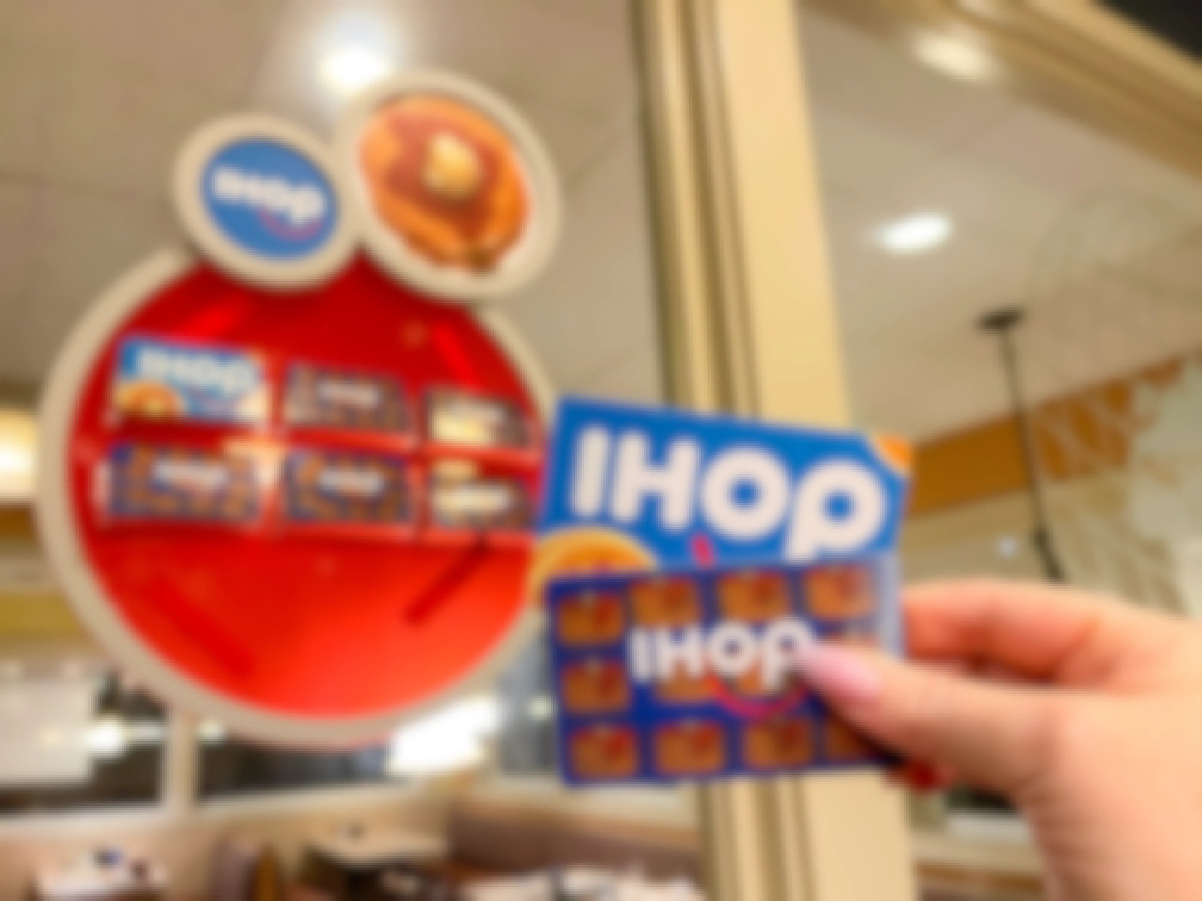 someone holding up two IHOP gift cards inside an IHOP restaurant