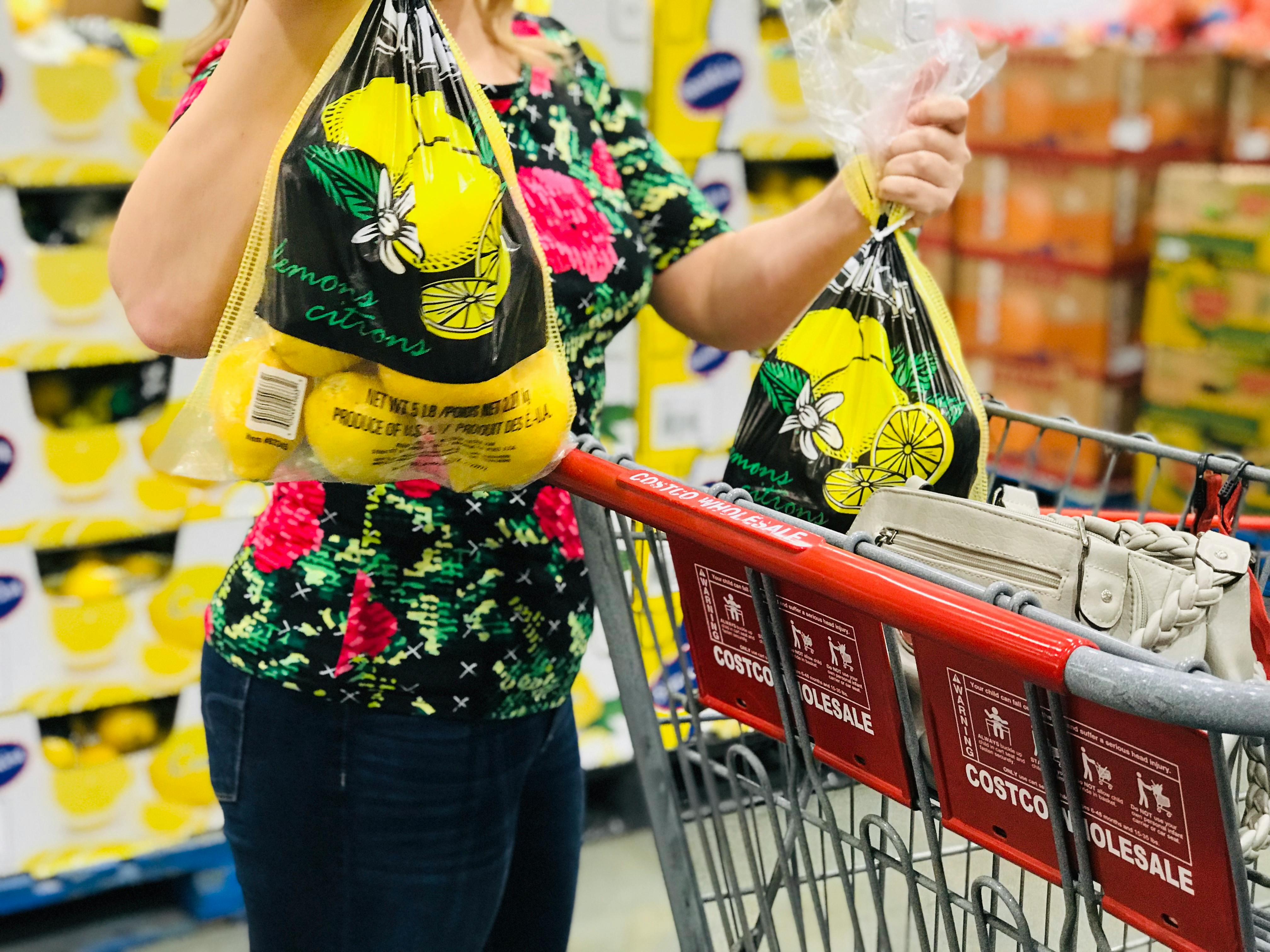 a person putting two bags of lemons into a costco cart 