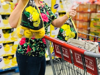 a person putting two bags of lemons into a costco cart