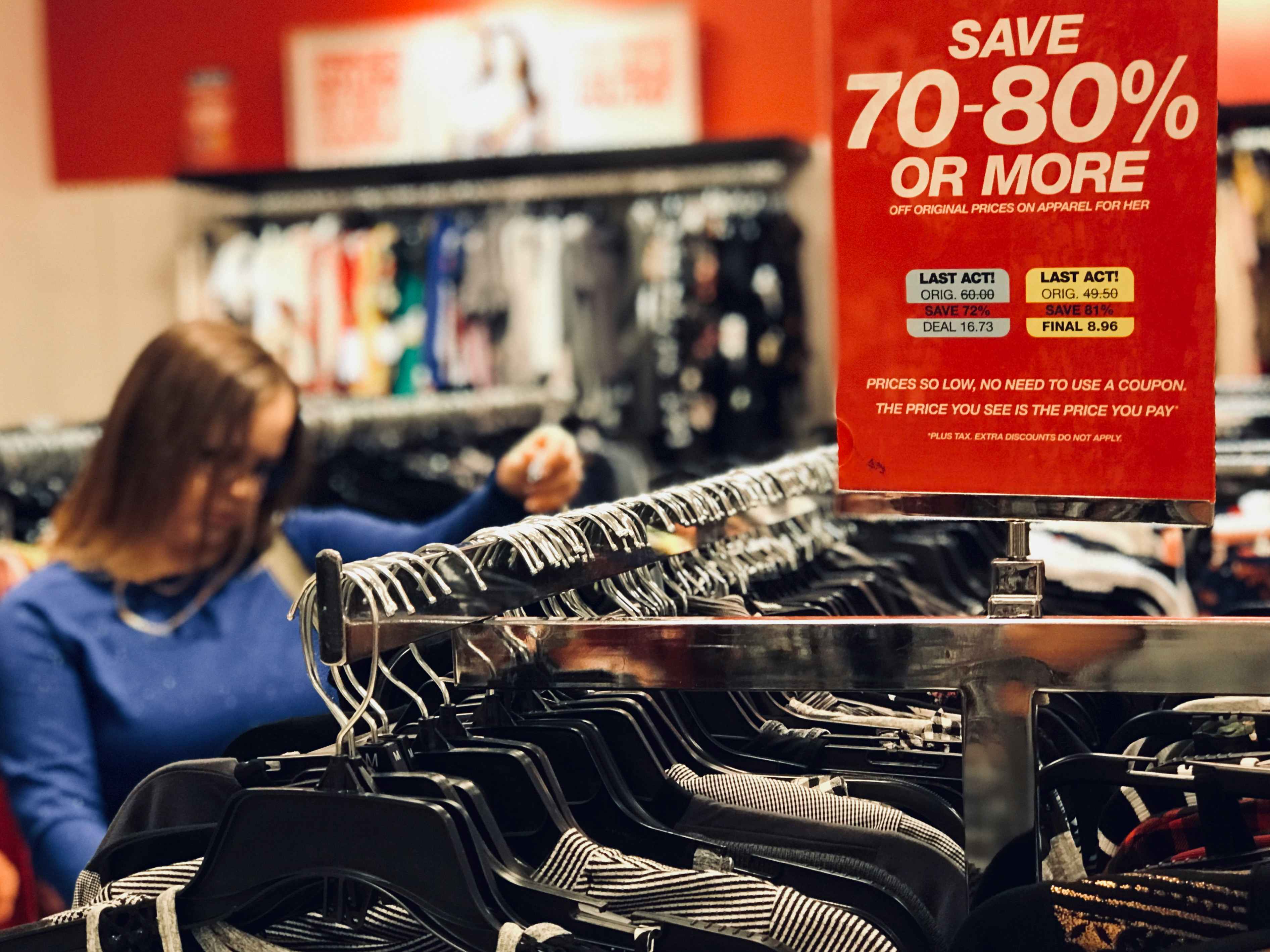woman shopping through clothes on macys clearance rack