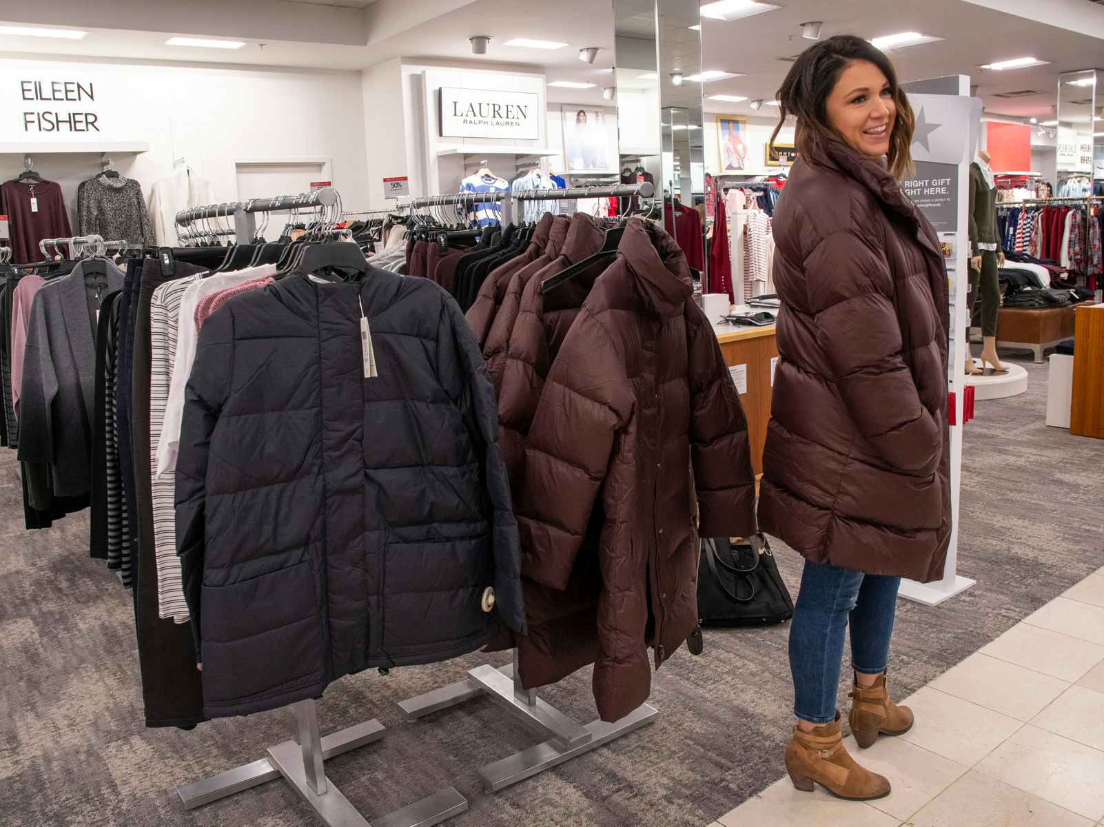 A woman trying on a winter coat in a Macy's department store.