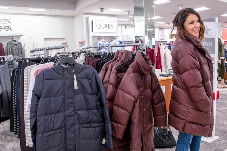person trying on winter coats at macys