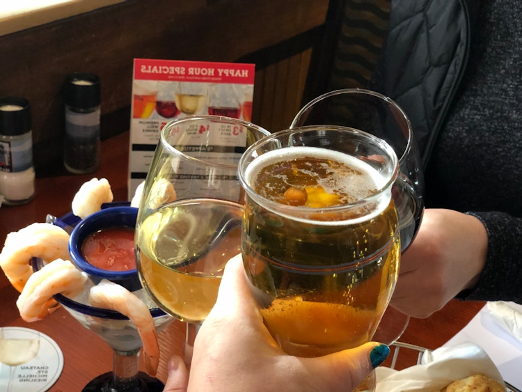People clinking their wine and beer glasses together above a shrimp cocktail appetizer at Red Lobster.