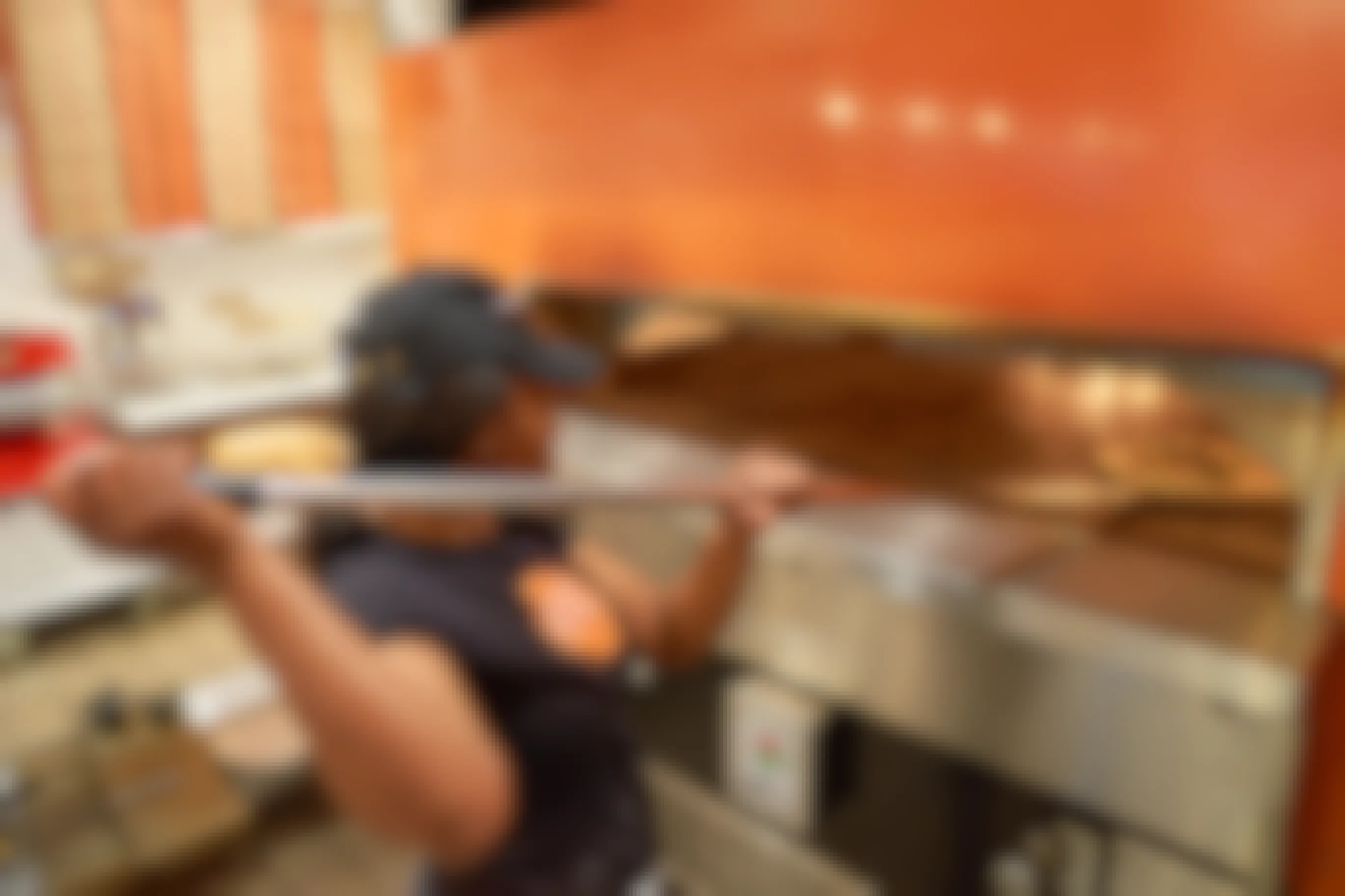 A Blaze Pizza employee pulling a pizza out of their oven with a giant wooden spatula.