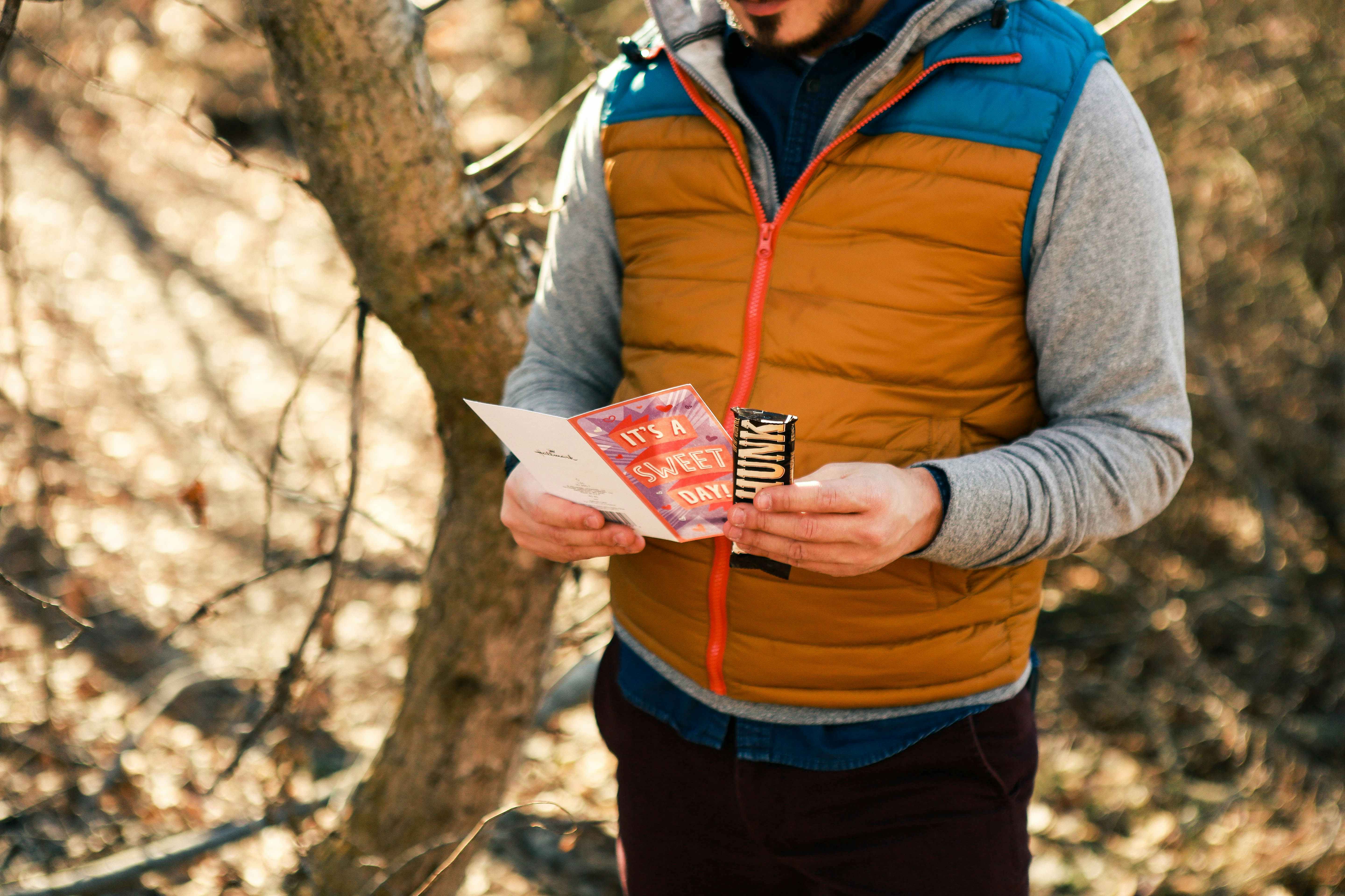 a man looking at a card and candy in the woods 