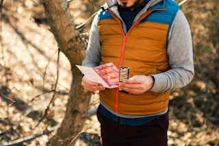 a man looking at a card and candy in the woods