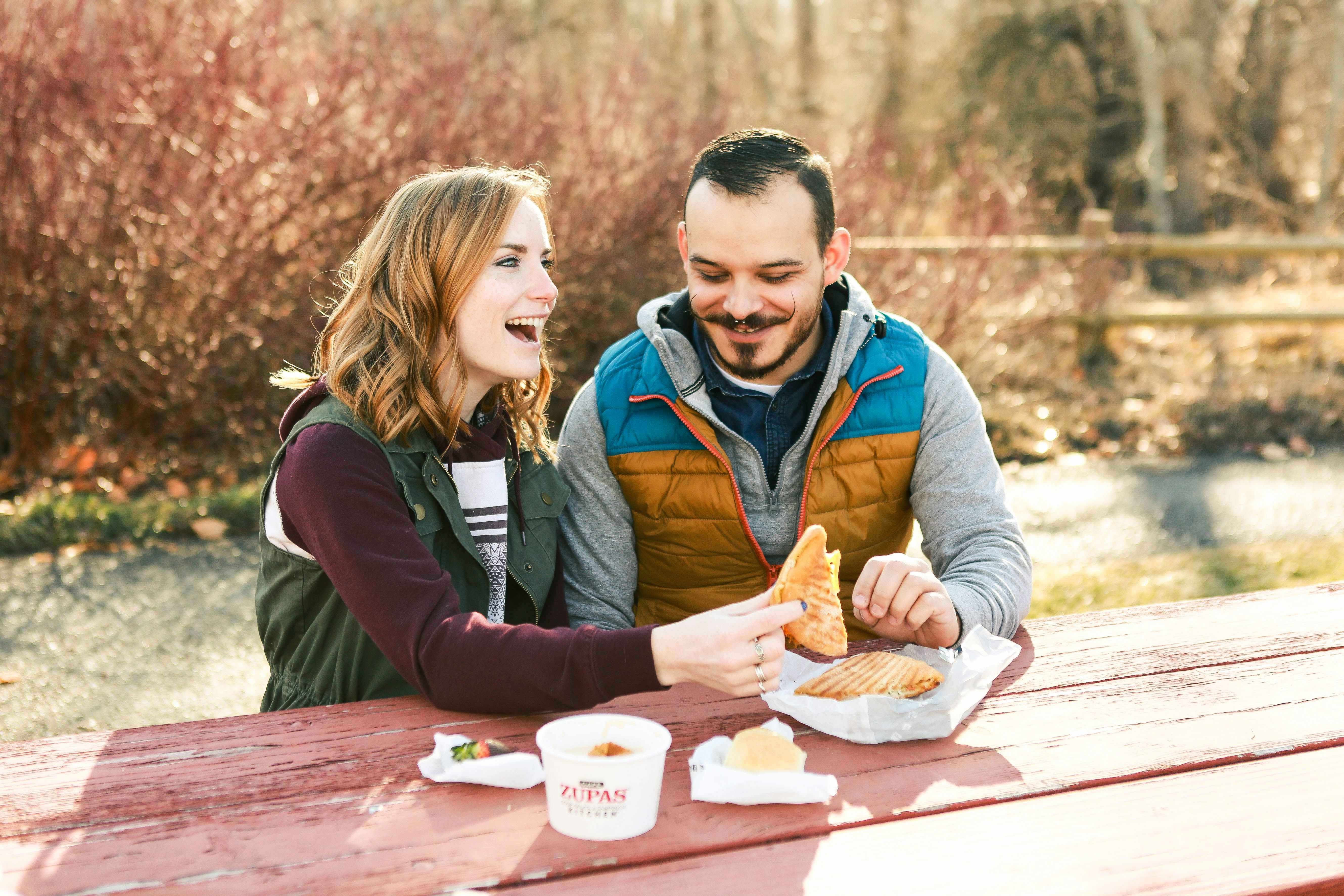 a couple eating at a picnic table 