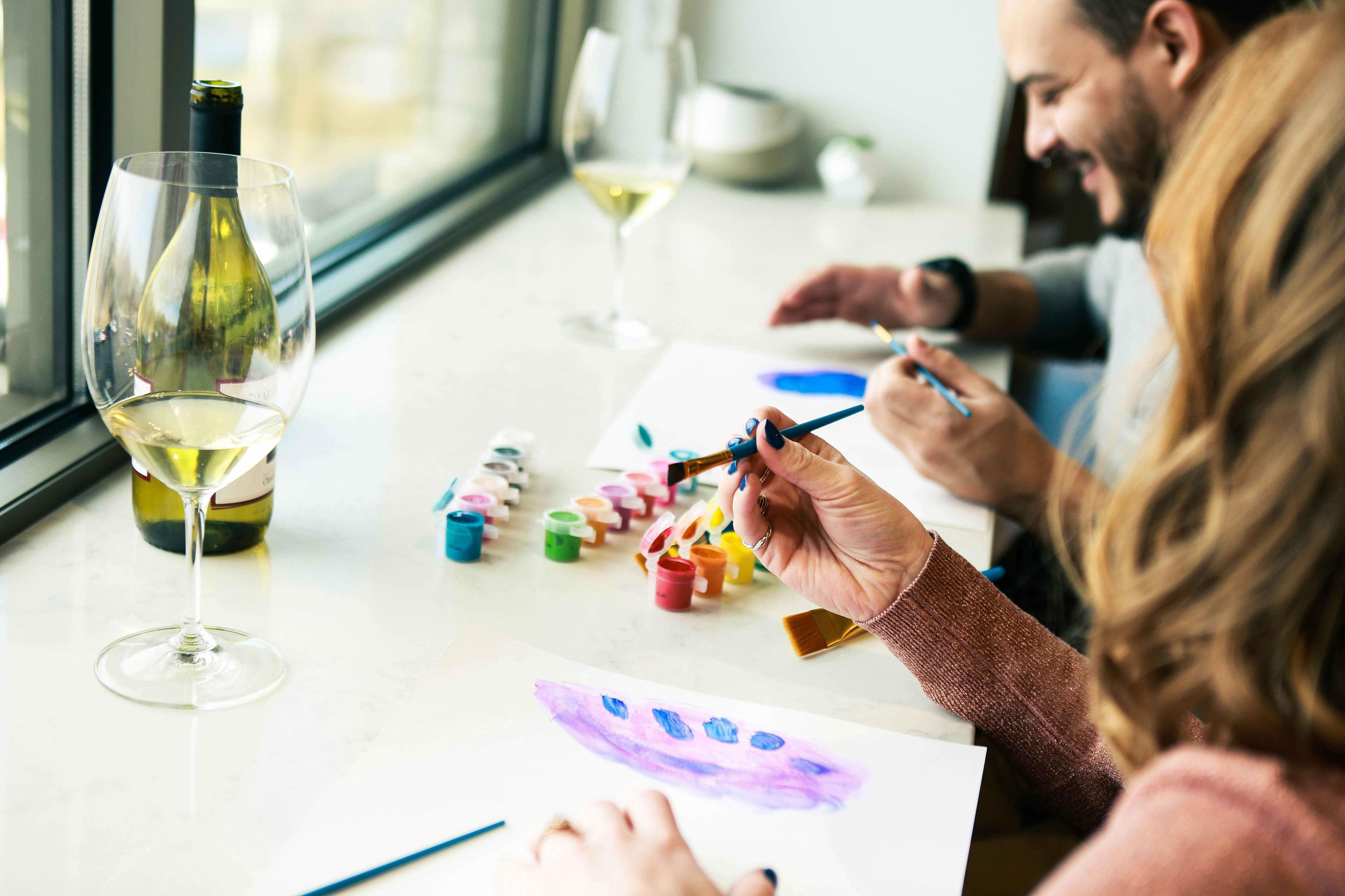 a couple painting together while drinking wine 