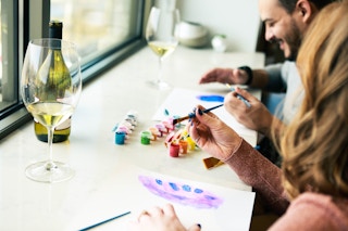 a couple painting together while drinking wine