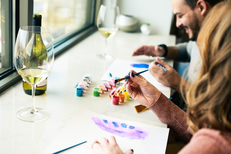 a couple painting together while drinking wine 