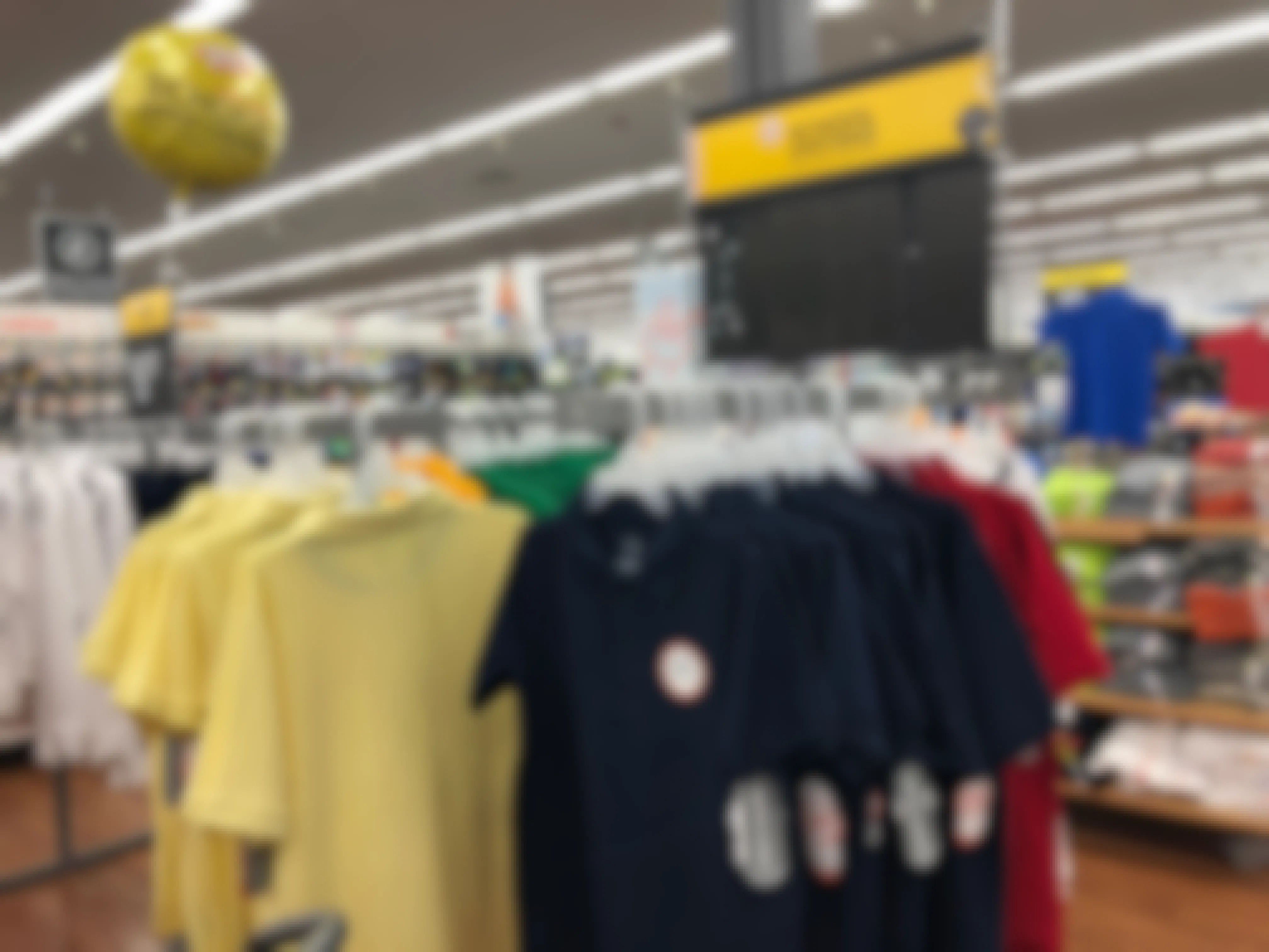 A rack of polo shirts with a sign and a balloon that both read, "School uniforms" inside Walmart.