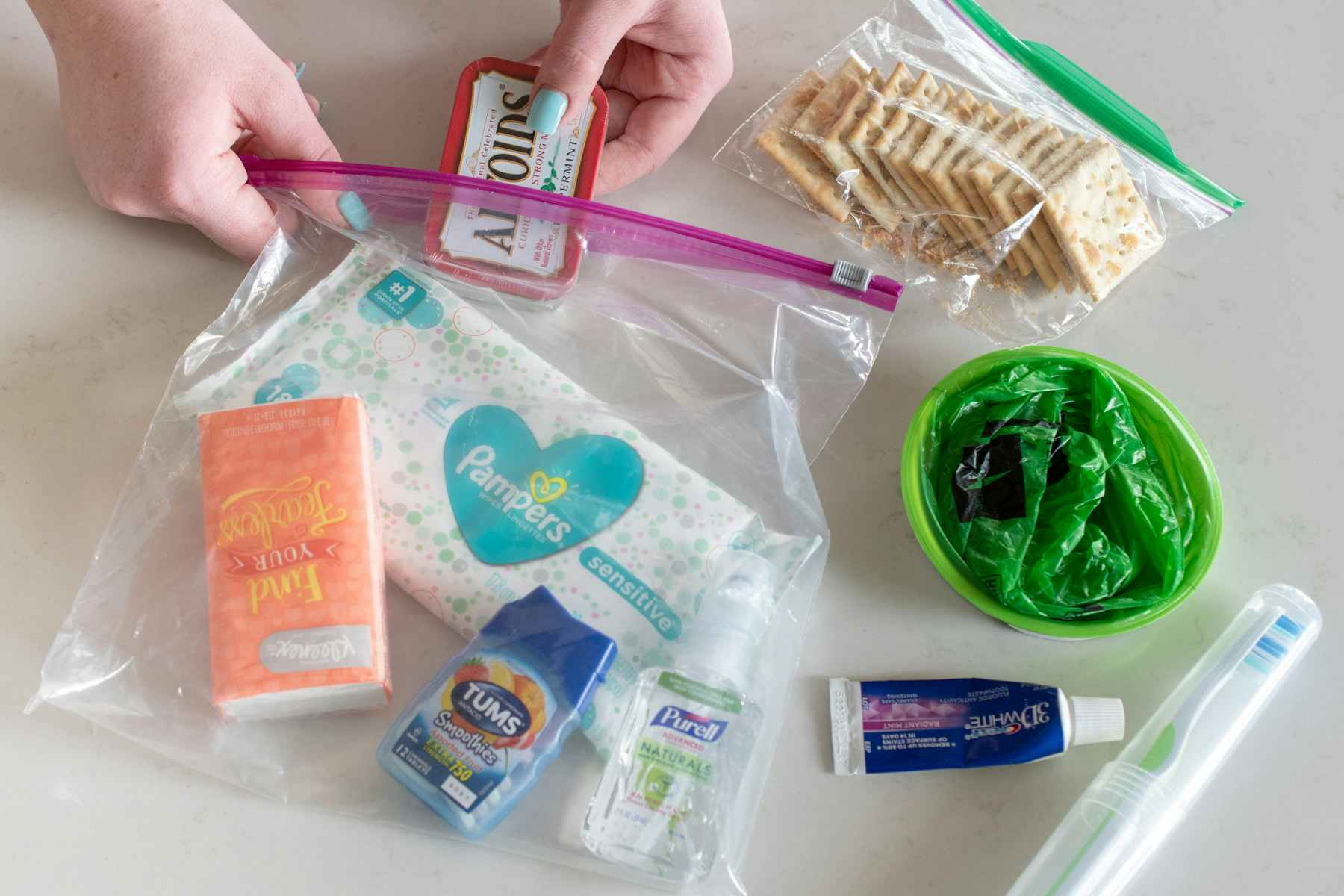 A person putting a container of Altoids into a baggie.