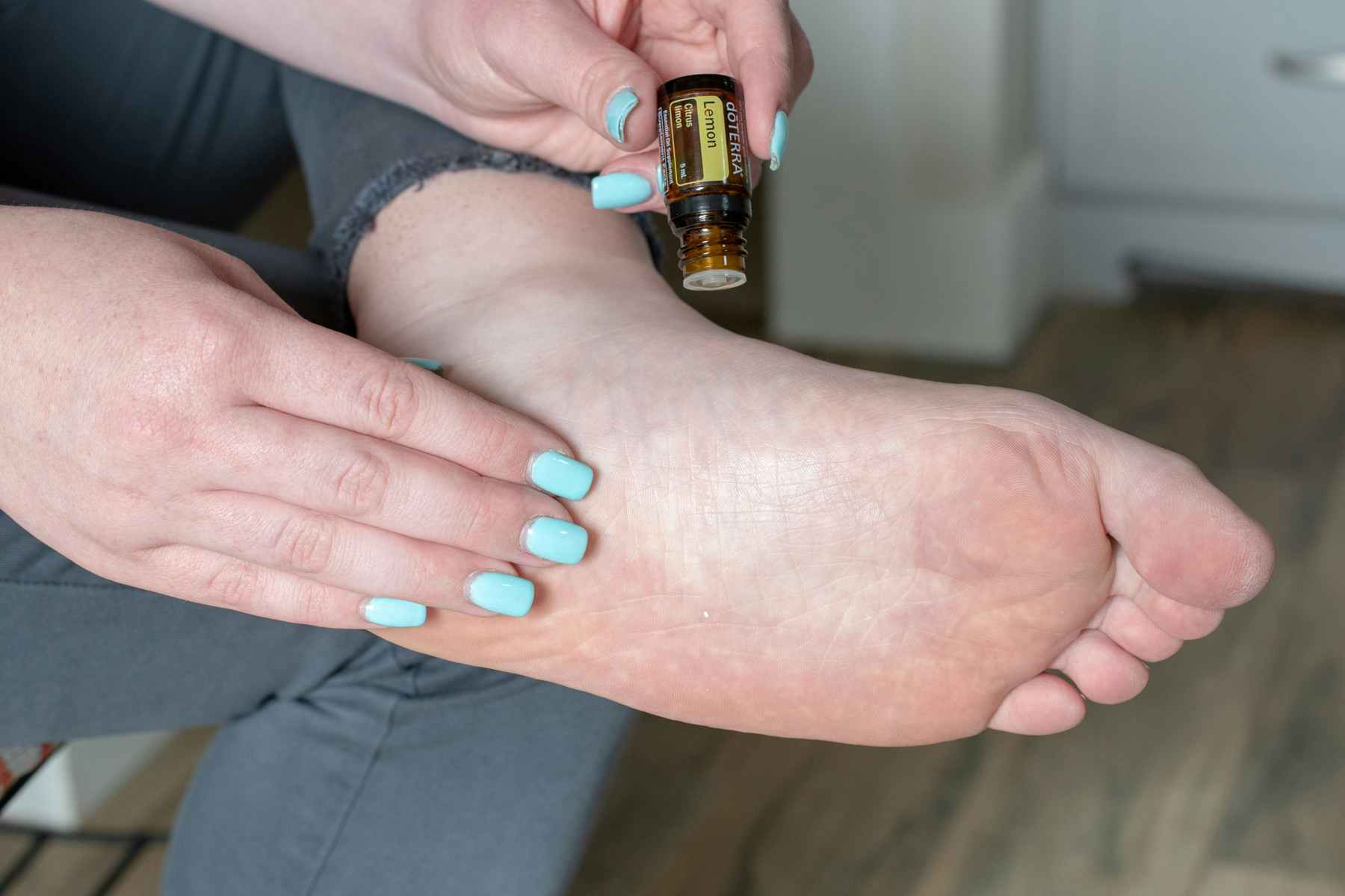 A person is putting essential oil on their foot.
