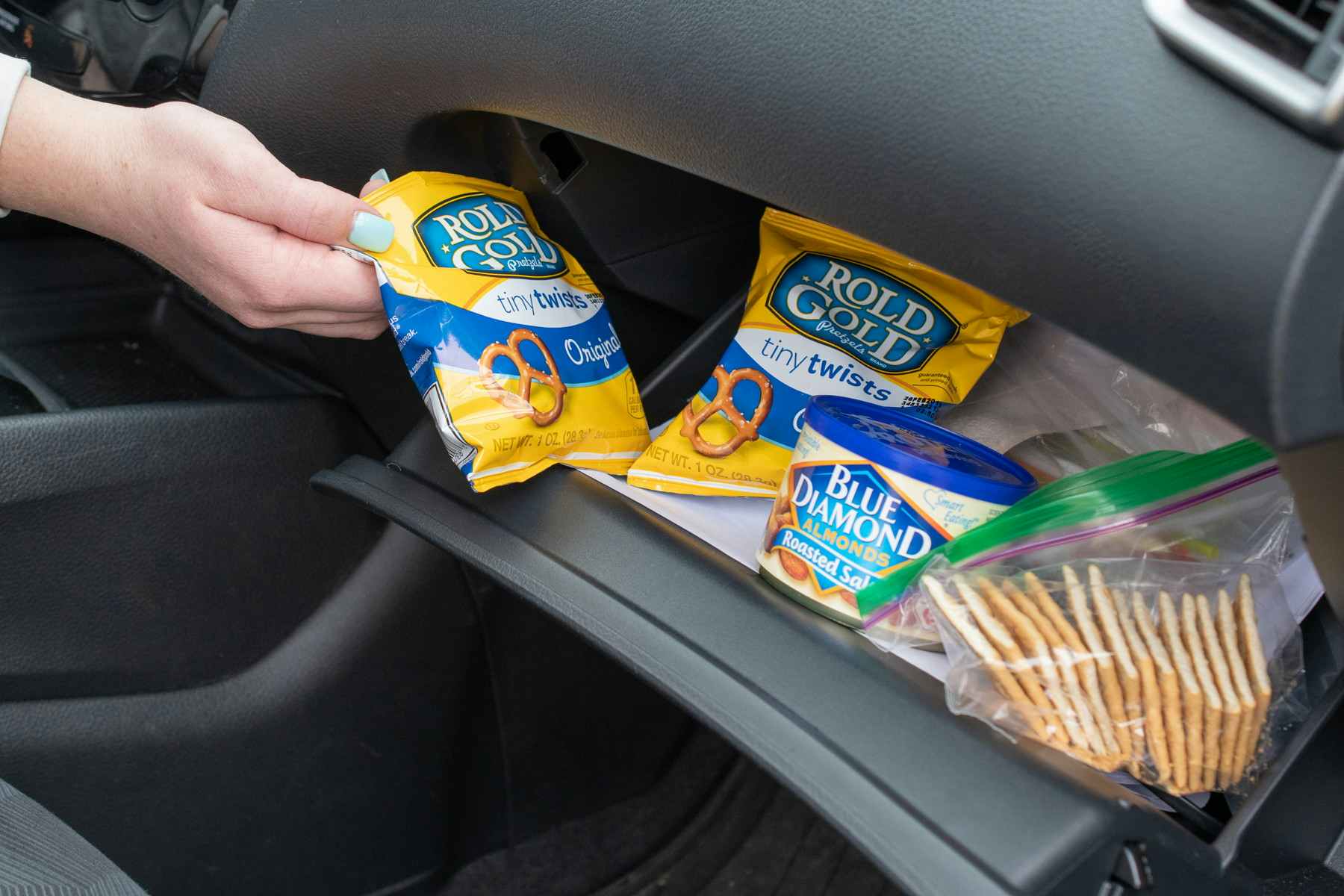 A person holding a bag of pretzels in a car.
