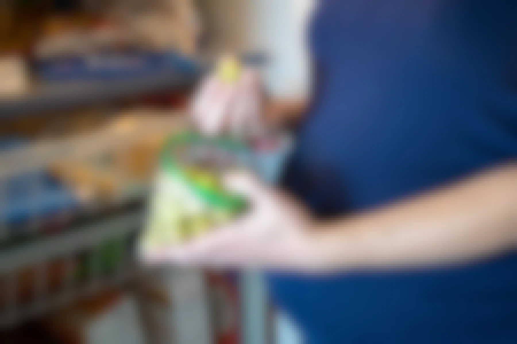 A pregnant woman holding a baggie of grapes in front of an open refrigerator.