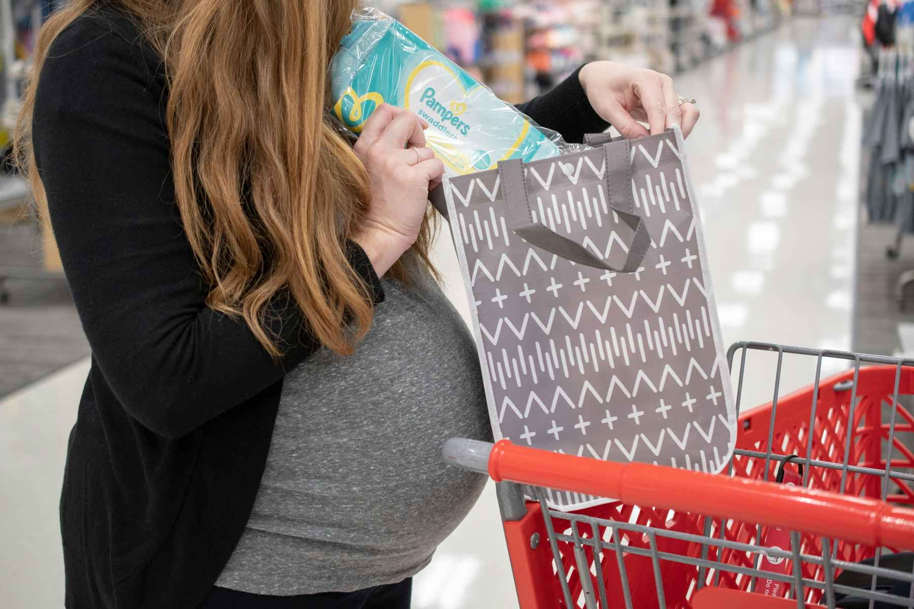 A pregnant woman holding a bag with Pampers diaper sample .