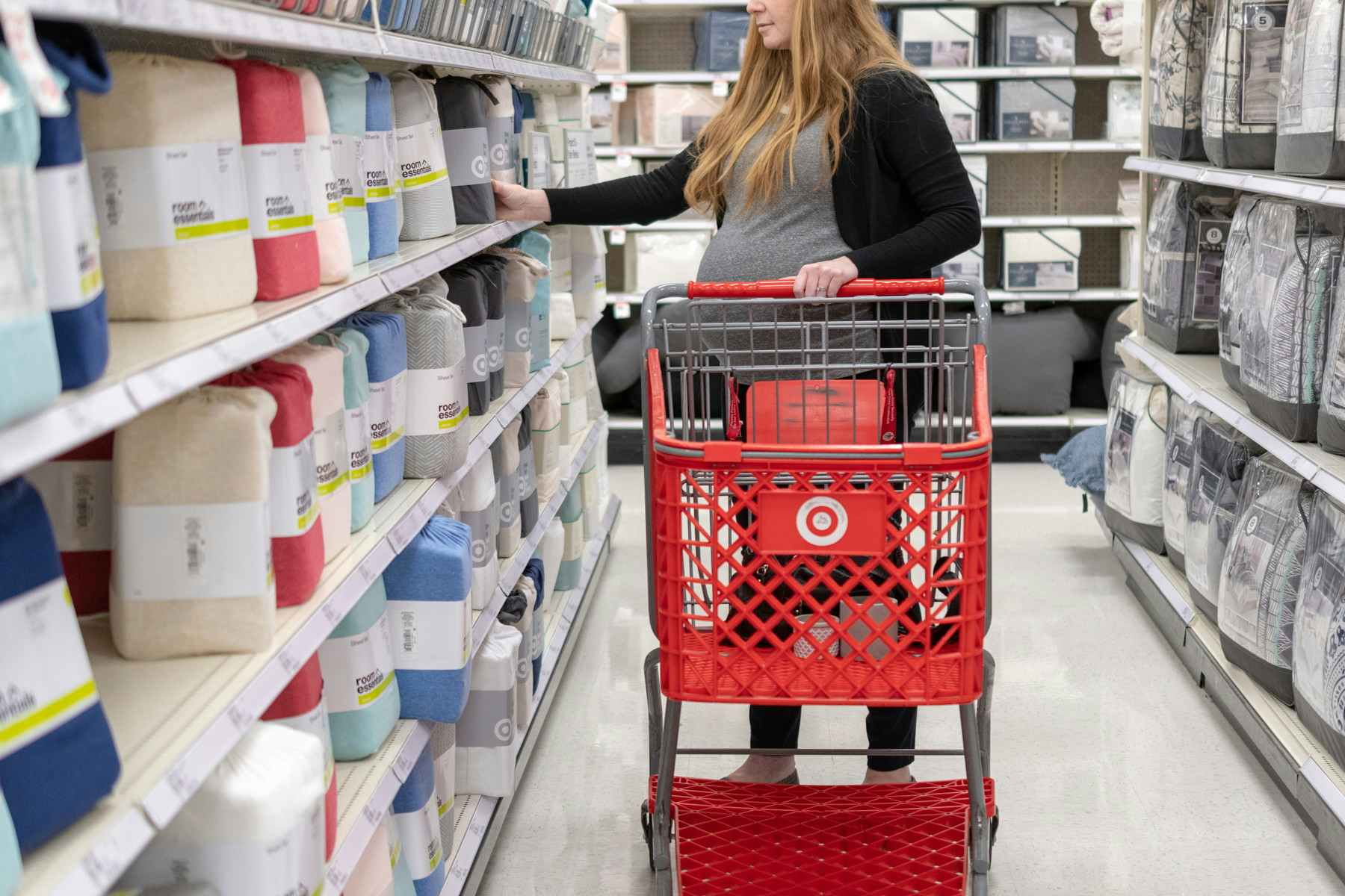 A pregnant woman looking at sheets at Target.