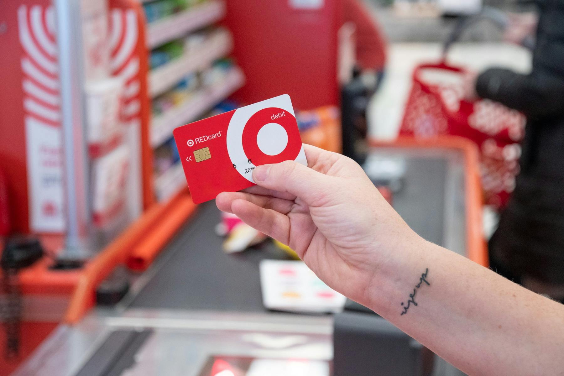 A person's hand holding a Target RedCard up in front of the checkout lane at Target.