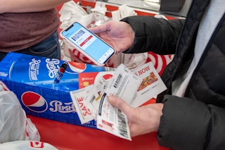 Person holding coupons at checkout.