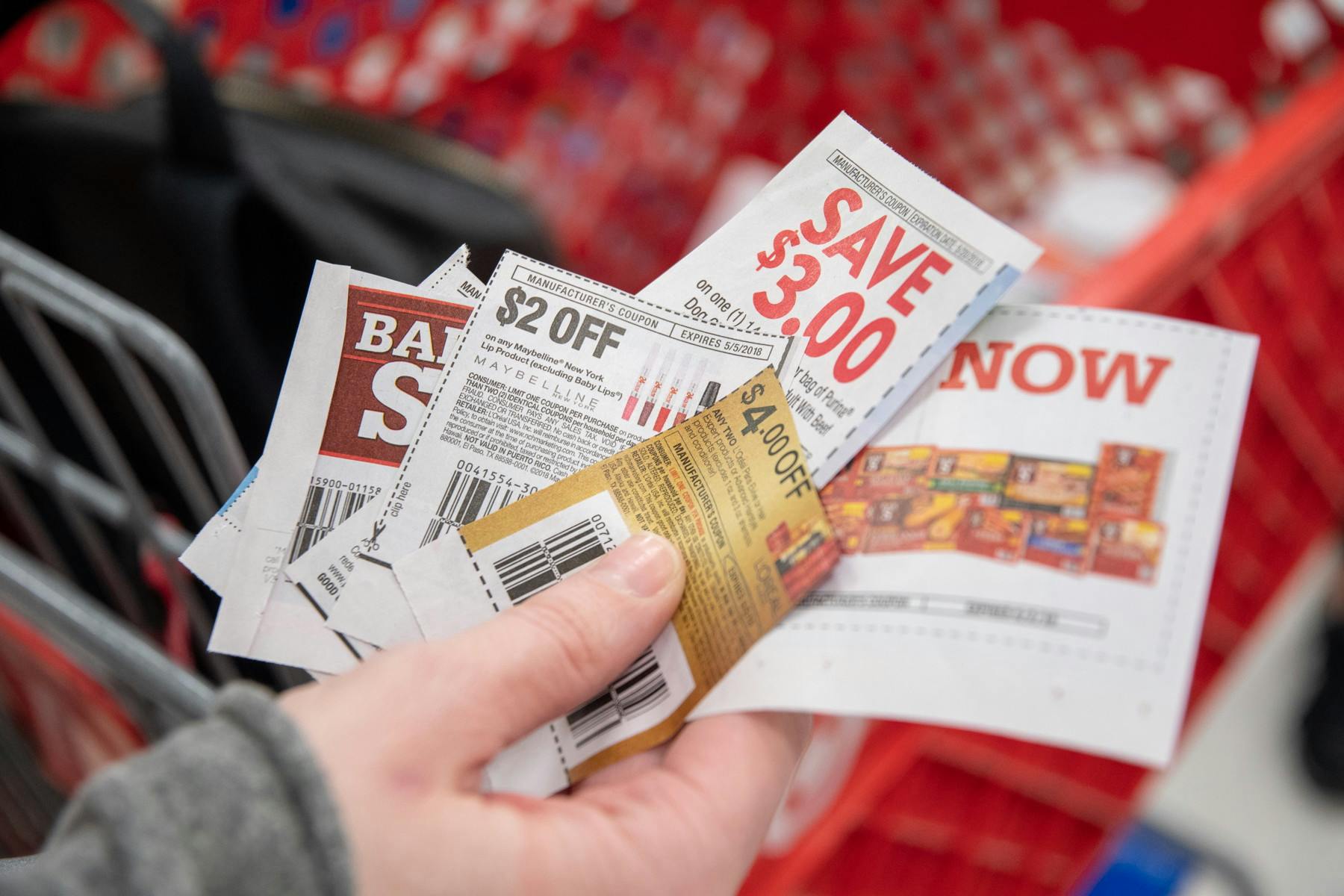 person holding manufacturer coupons near target cart